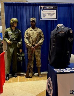 USAF Airman in uniform standing next to display.