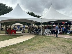 Attendees sit under two white tents and listen to speakers at the Military Working Dog Teams National Monument 10 Year Commemoration.