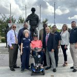 Members of the Airman Heritage Foundation stand in front of the Military Working Dog Teams National Monument with the creator of the monument, John Burnam.