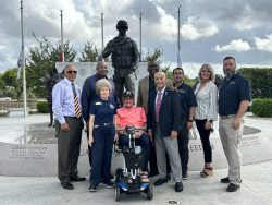 Members of the Airman Heritage Foundation stand in front of the Military Working Dog Teams National Monument with the creator of the monument, John Burnam.