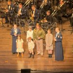 The Band of the West spotlighted the 75th Anniversary of the end of the Berlin Airlift with a dramatic reenactment featuring the "Candy Bomber" alongside anxious German children. Small parachutes with candy were dropped from the upper catwalks onto the audience below for effect.